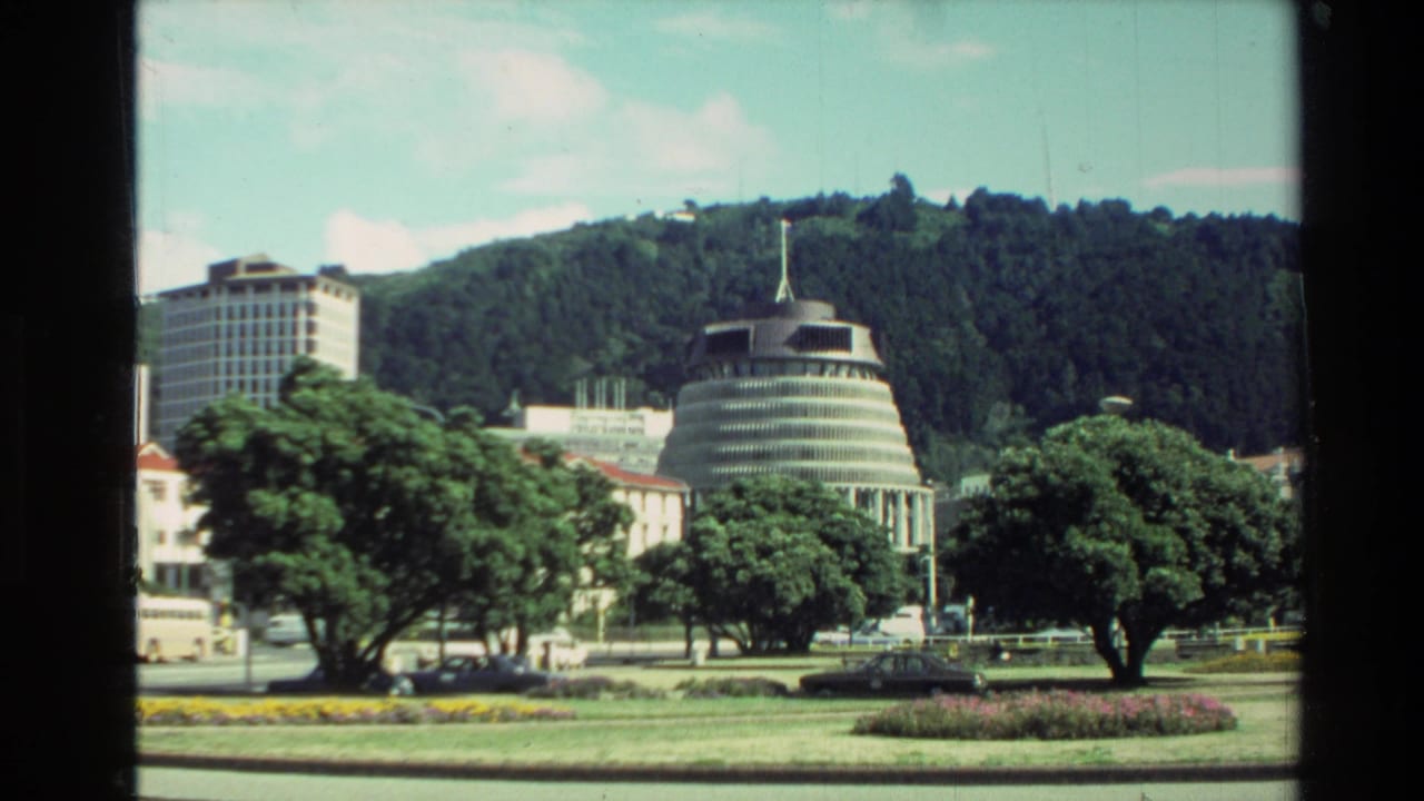The Beehive, gardens, trees, and street traffic appear in a bright Wellington city view from 1981.