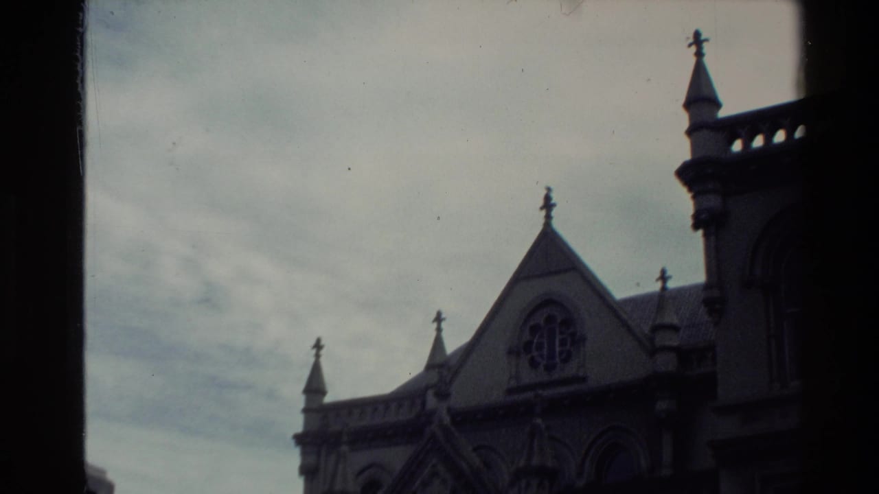 1981 New Zealand 8mm frame showing a Gothic-style building with spires, crosses, arched detail, and a circular window behind a dark vertical frame.