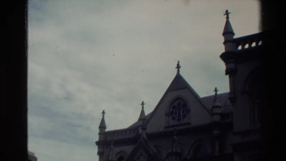 1981 New Zealand 8mm frame showing a Gothic-style building with spires, crosses, arched detail, and a circular window behind a dark vertical frame.