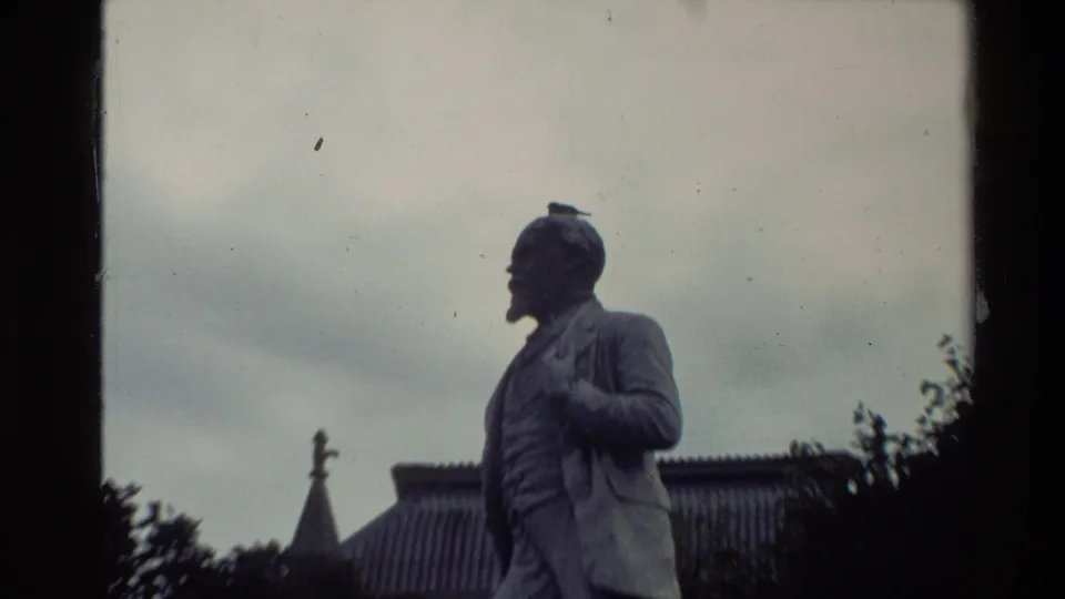 1981 New Zealand 8mm frame showing a closer side view of the suited stone statue, with a small bird perched on the statue's head.