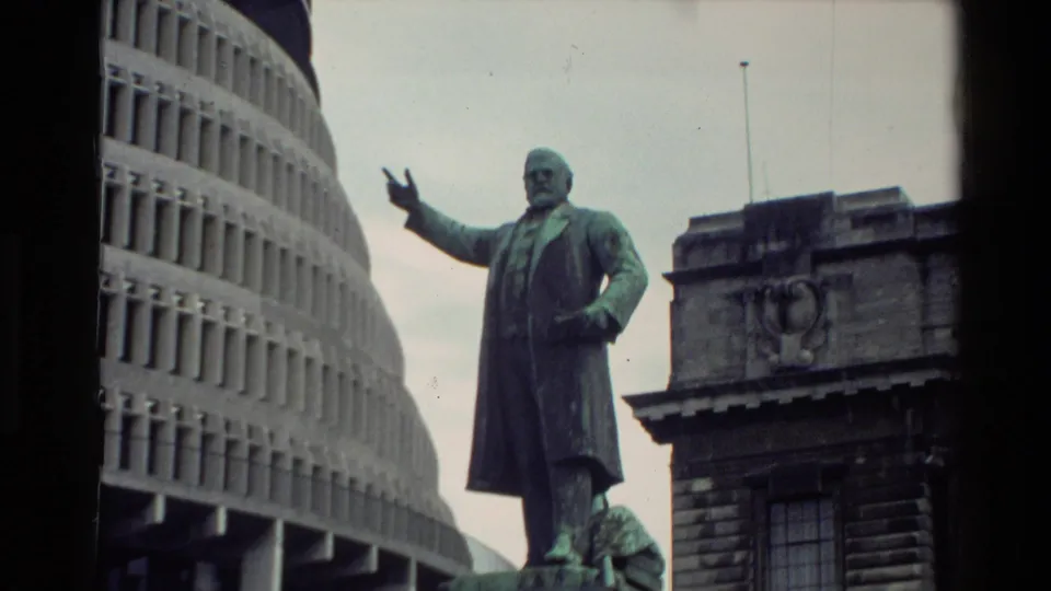 1981 New Zealand frame showing a standing public statue near Wellington's circular Beehive building and adjacent civic architecture.