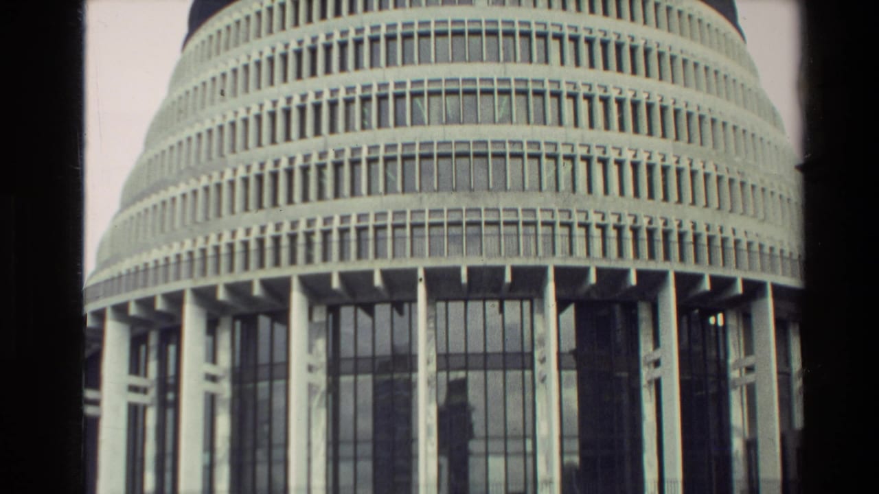 Closer view of the Beehive facade with vertical windows, concrete columns, and pale sky.