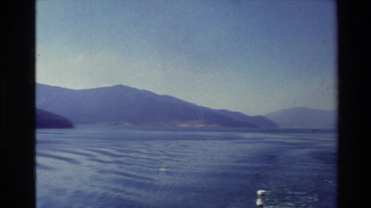 Open blue lake with distant mountains and a small white boat wake.