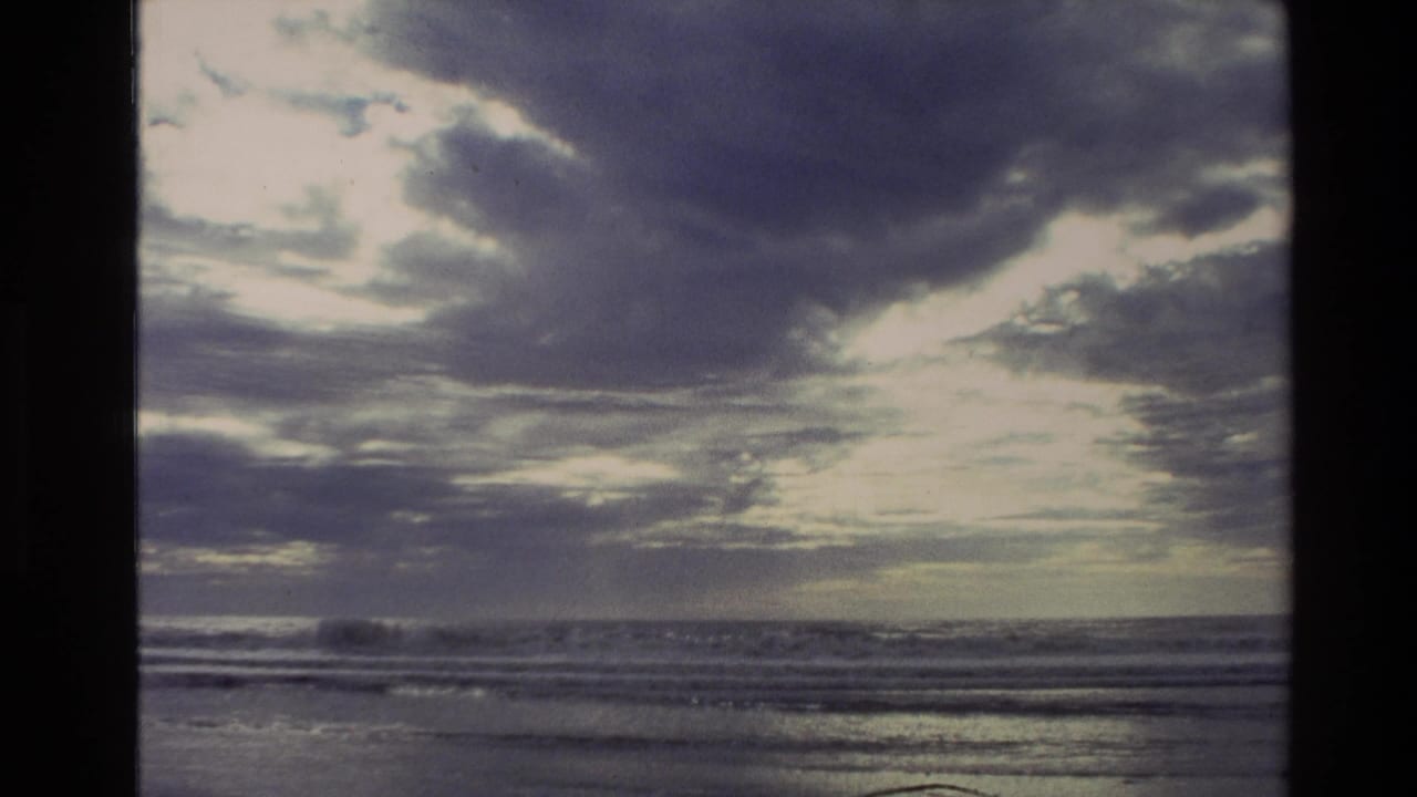 Sunlit clouds over ocean waves with a dark film border at the side.