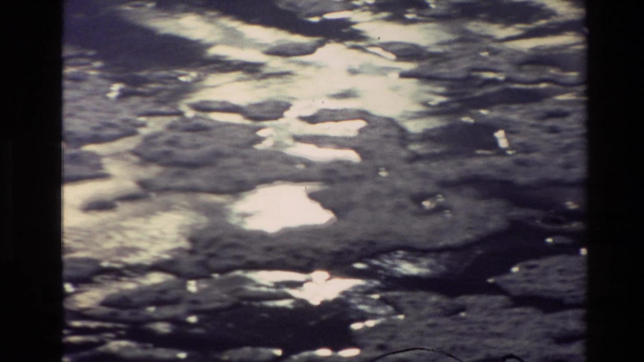 1982 New Zealand 8mm frame showing rippled river water with strong reflected light and dark floating patches.