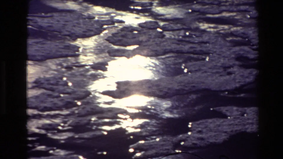 Vintage 8mm frame showing shimmering river water in New Zealand, with blown highlights and textured ripples.
