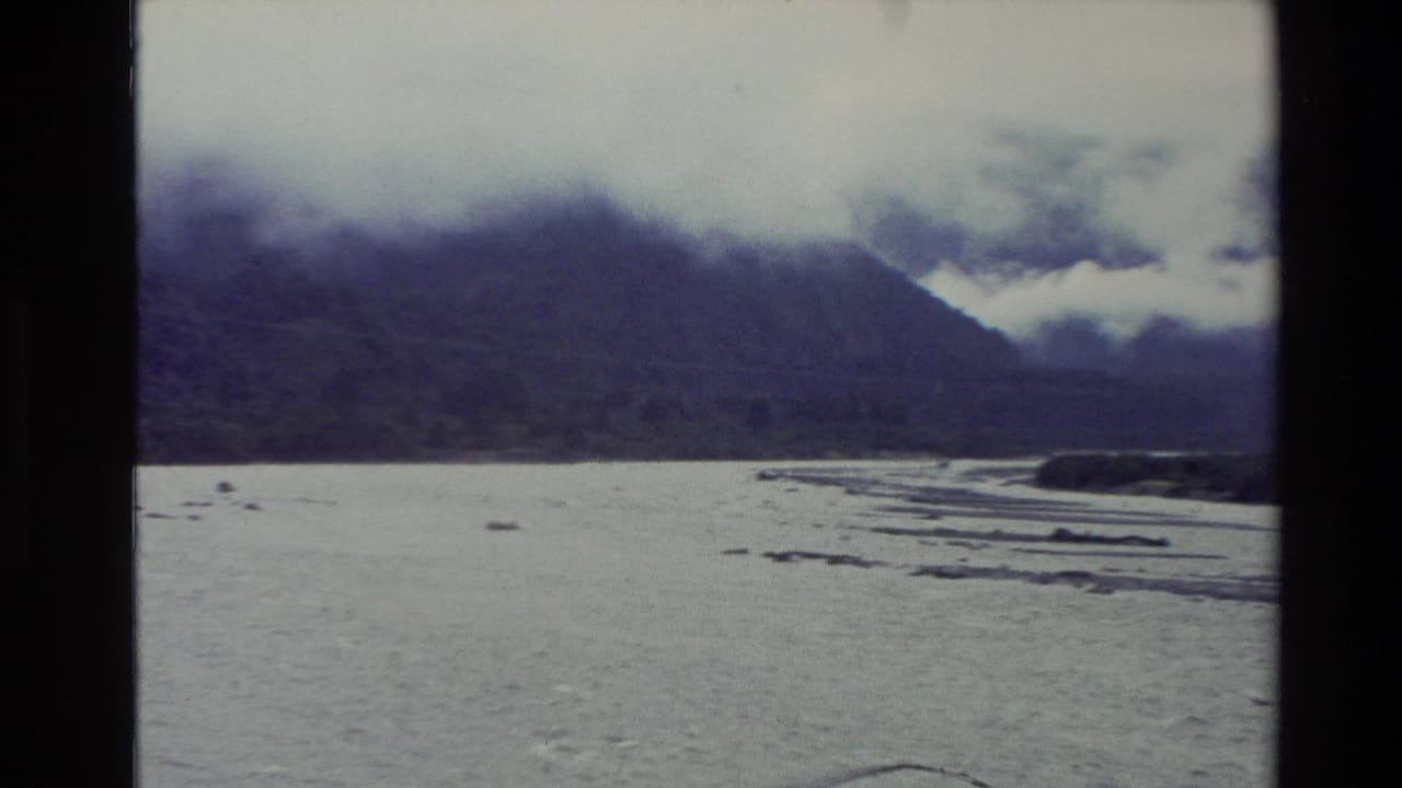 Wide river and gravel bars with mountains partly hidden by cloud.