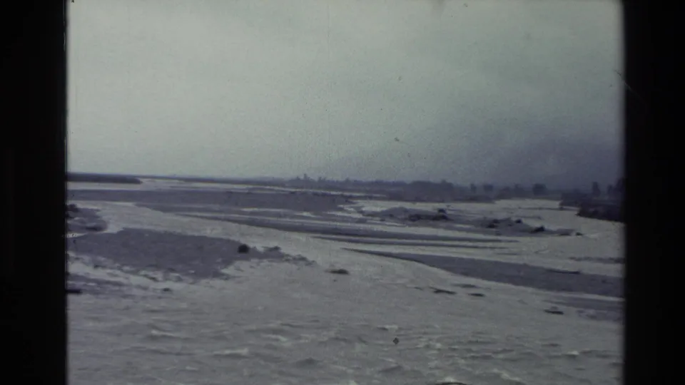 1982 New Zealand 8mm view of river flats and braided channels receding into haze under an overcast sky.
