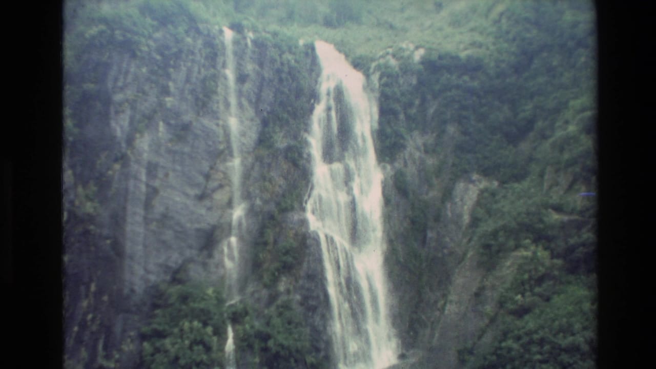 Tall waterfall streaming over a steep rock face surrounded by trees.