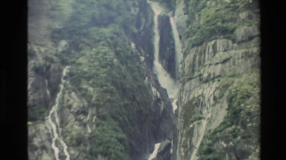 1982 New Zealand 8mm frame with a tall waterfall on the right and smaller cascades threading through a steep rocky gorge.