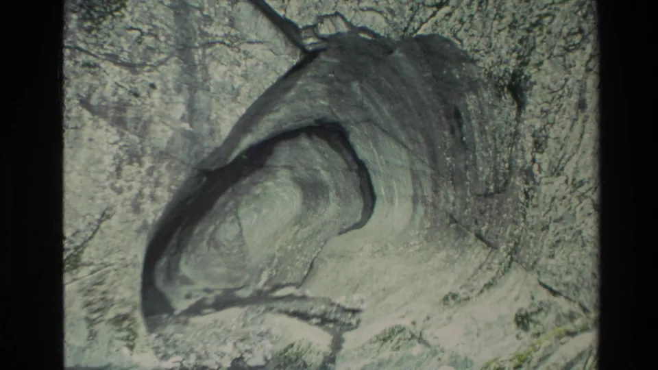 1982 New Zealand 8mm frame with a closer view of a dark hollow cavity carved into a pale rock surface.