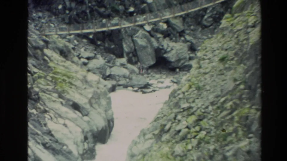 1982 New Zealand home-movie frame looking down a rocky gorge with bright rushing water and a bridge line overhead.