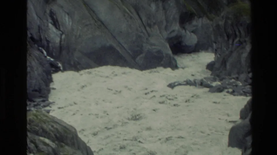 A 1982 New Zealand travel frame shows rushing river water confined between steep, dark rocks below the bridge.