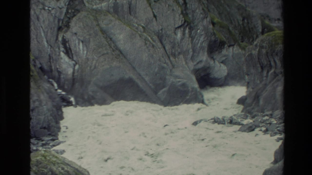 Muddy water rushing through a narrow rocky canyon with steep stone walls.