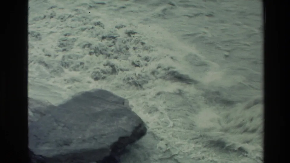 1982 New Zealand 8mm frame showing white rapids and rough water moving around dark rocks below the canyon viewpoint.