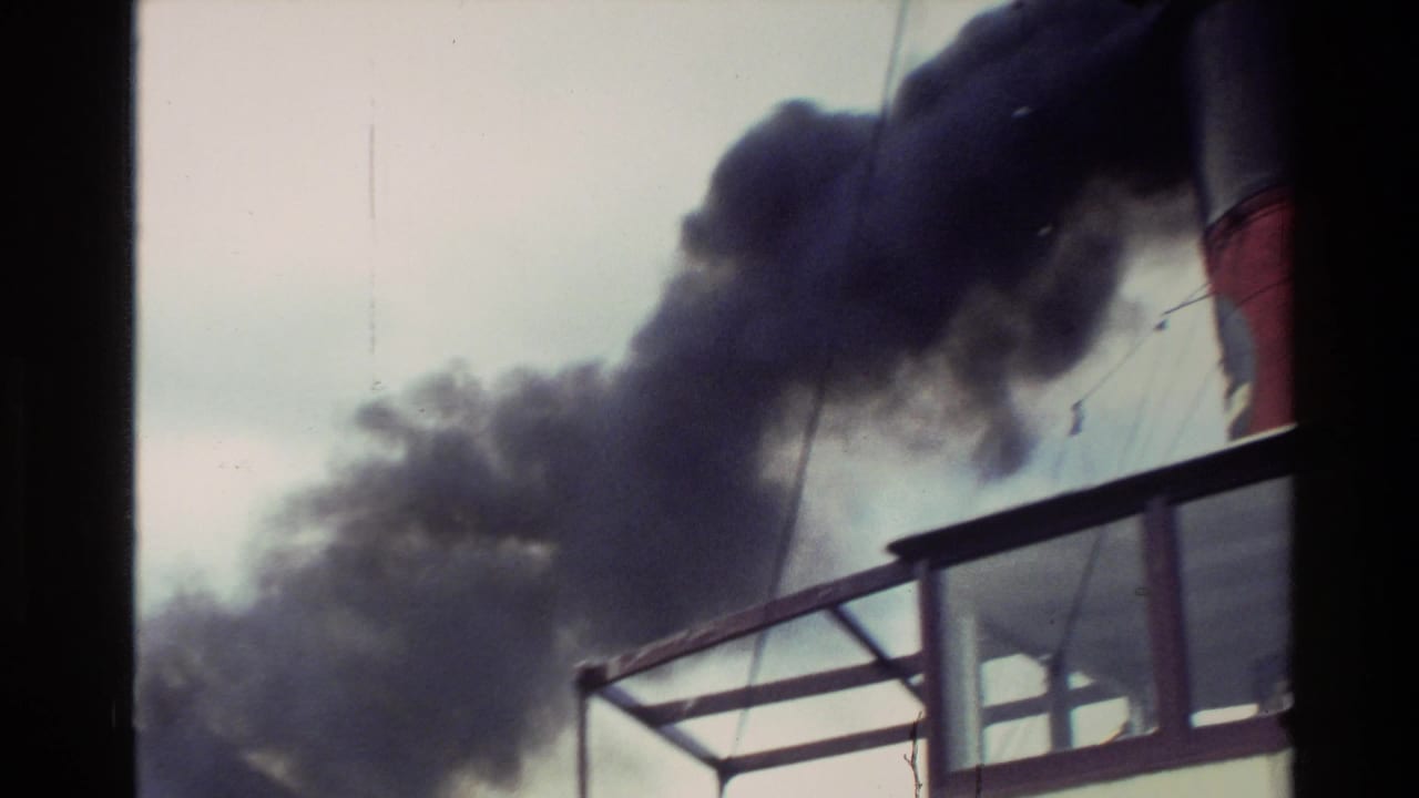1982 New Zealand 8mm frame showing dark exhaust from a red-and-black boat smokestack above deck railings.