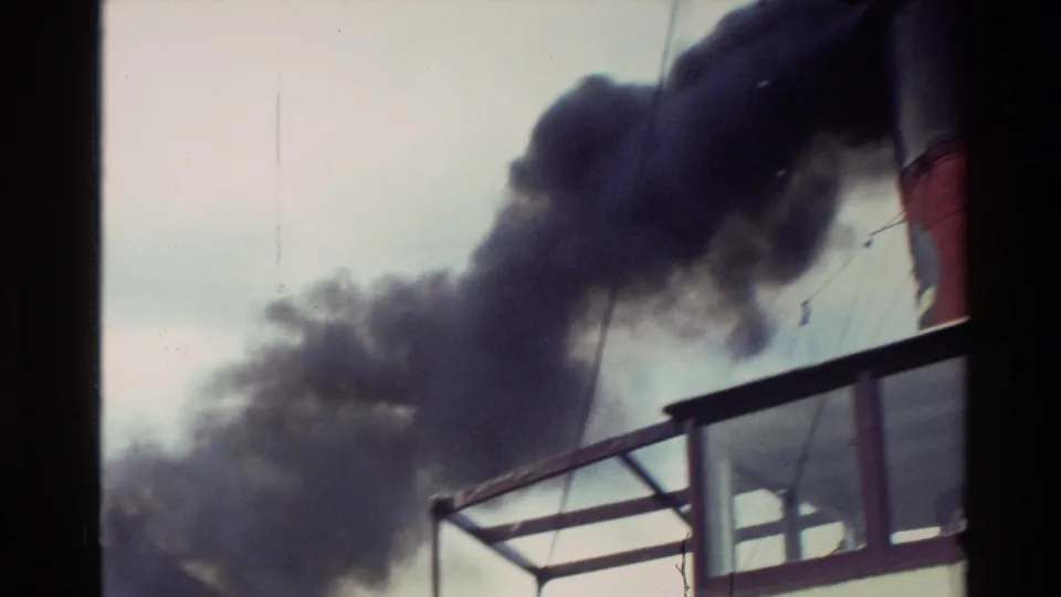 1982 New Zealand 8mm frame showing dark exhaust from a red-and-black boat smokestack above deck railings.