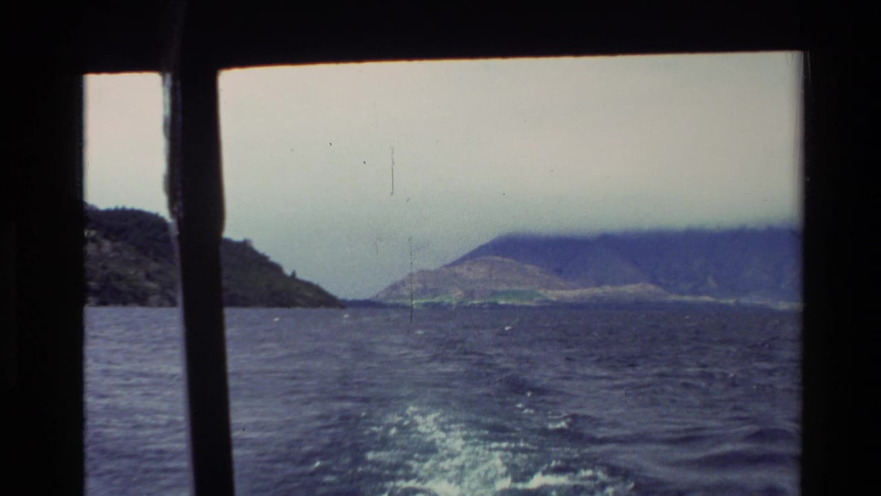 1982 New Zealand home-movie view from a moving boat, with choppy water, wake and distant forested mountains under cloud.