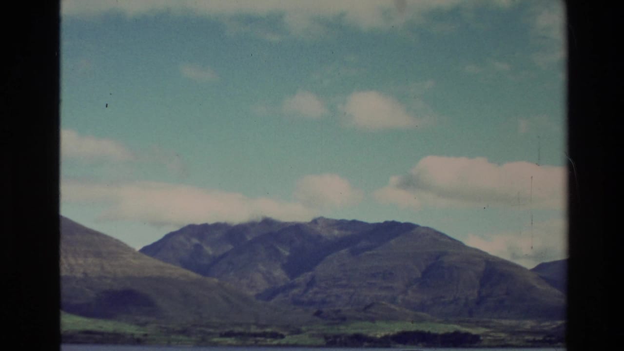 Mountain range and lake seen through dark vehicle window framing.