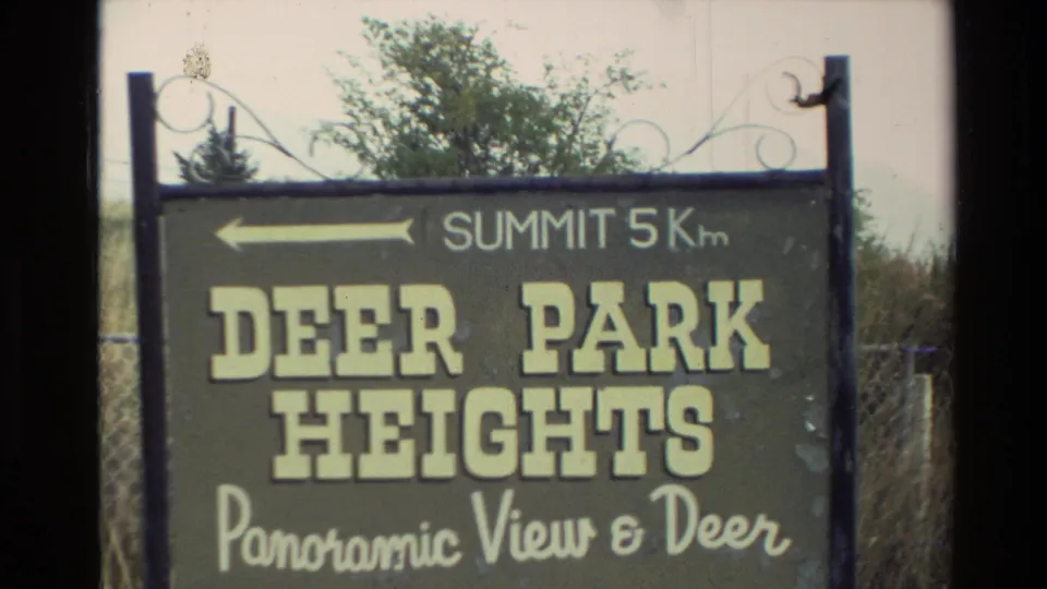 1982 New Zealand frame showing a Deer Park Heights roadside sign pointing toward a summit 5 km away.