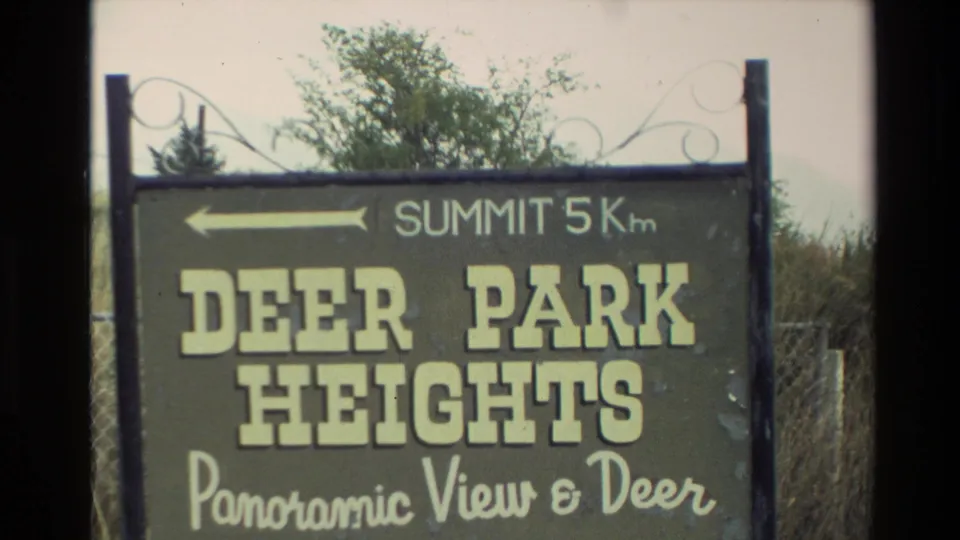 1982 New Zealand 8mm frame showing a Deer Park Heights sign with a summit direction and partial wording about panoramic views and deer.