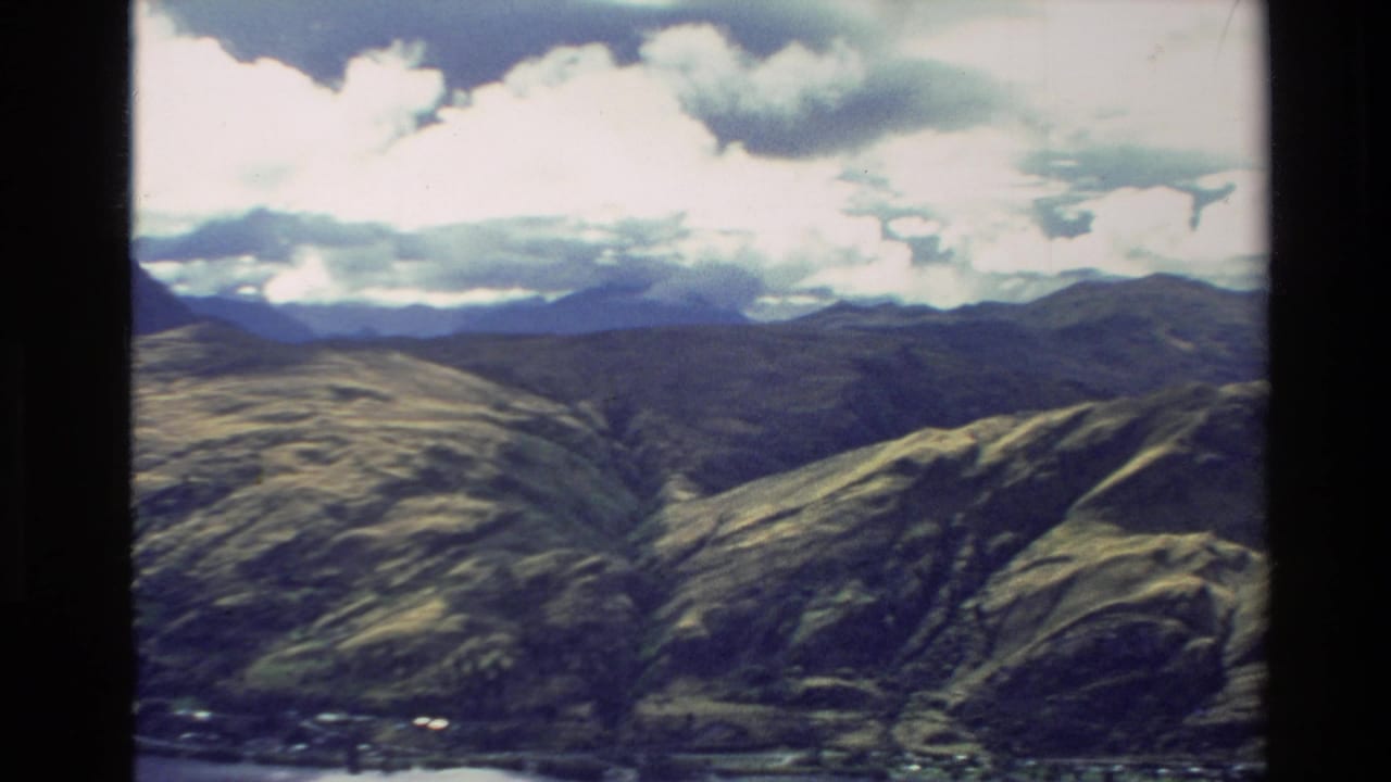 Aerial view of rounded mountain ridges beneath bright clouds.