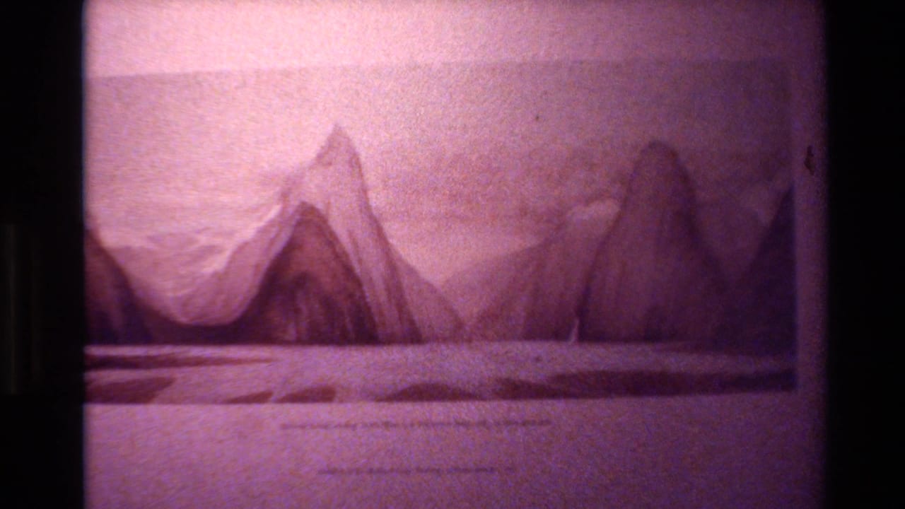 1982 New Zealand 8mm frame showing a filmed mountain-range illustration with pale sky, flat foreground, grain, and projector-edge darkness.