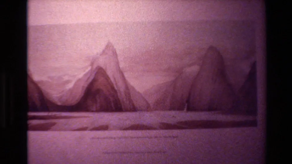1982 New Zealand 8mm frame showing the same mountain drawing, with a light sky, flat land or water foreground, faint markings, and aged color shift.