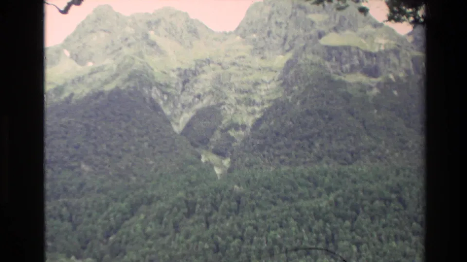 1982 New Zealand home-movie view of rugged mountain peaks, forested lower slopes, and faded 8mm color.