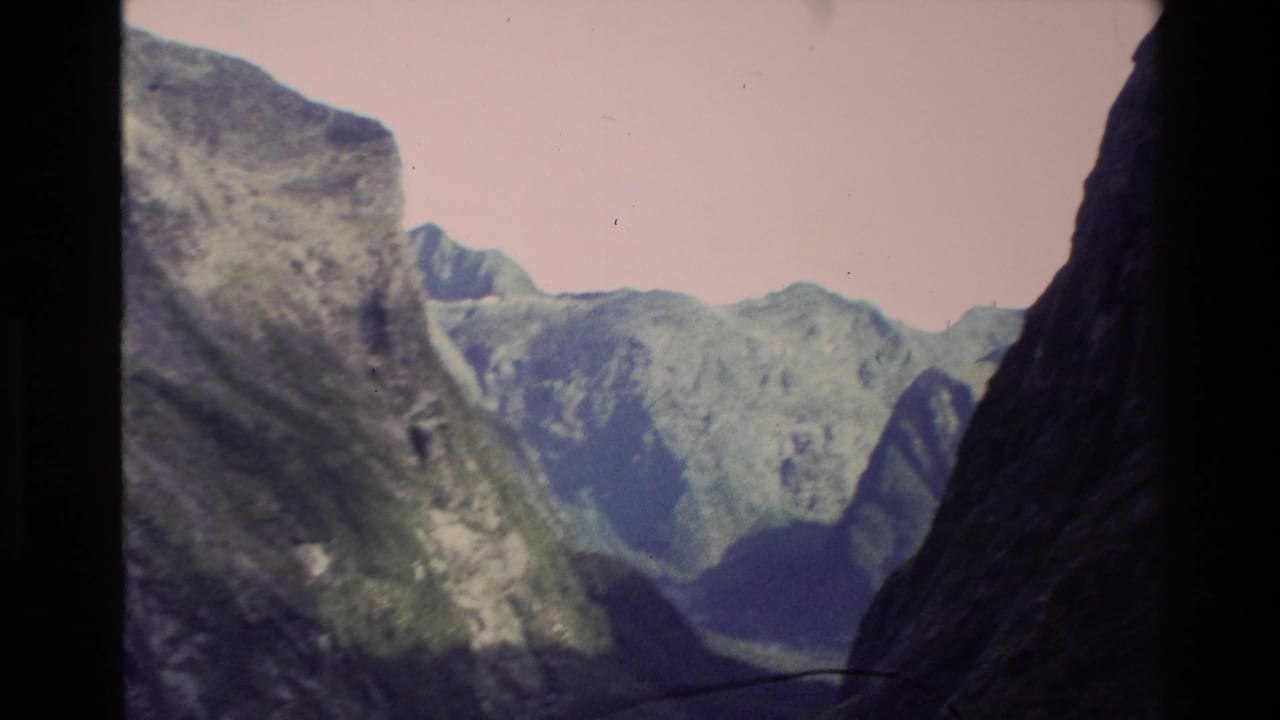 1982 New Zealand 8mm view into a narrow ravine bordered by steep green mountain walls and distant ridges.