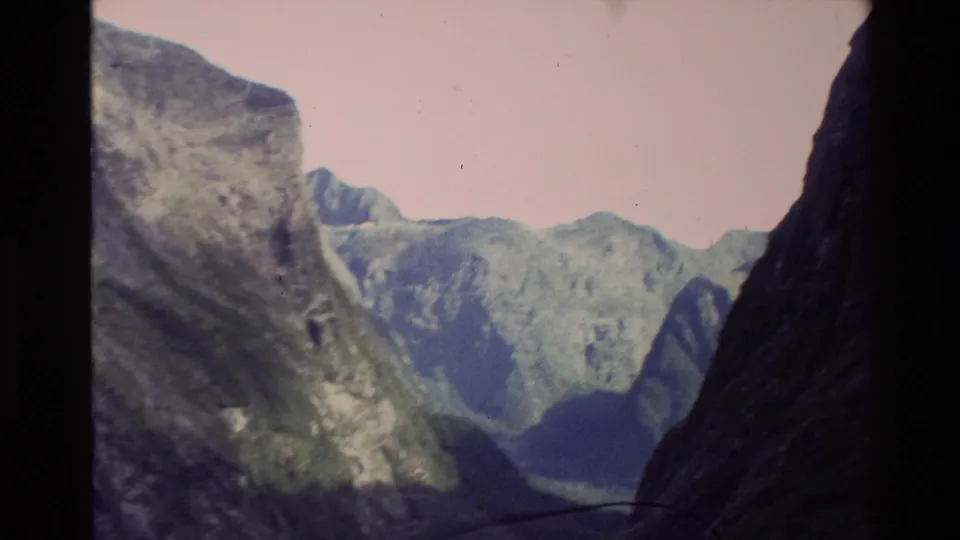 1982 New Zealand 8mm view into a narrow ravine bordered by steep green mountain walls and distant ridges.