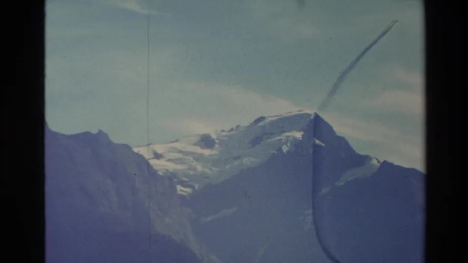 1982 New Zealand 8mm frame with a snow-dusted mountain peak, rugged surrounding slopes, and visible film wear.