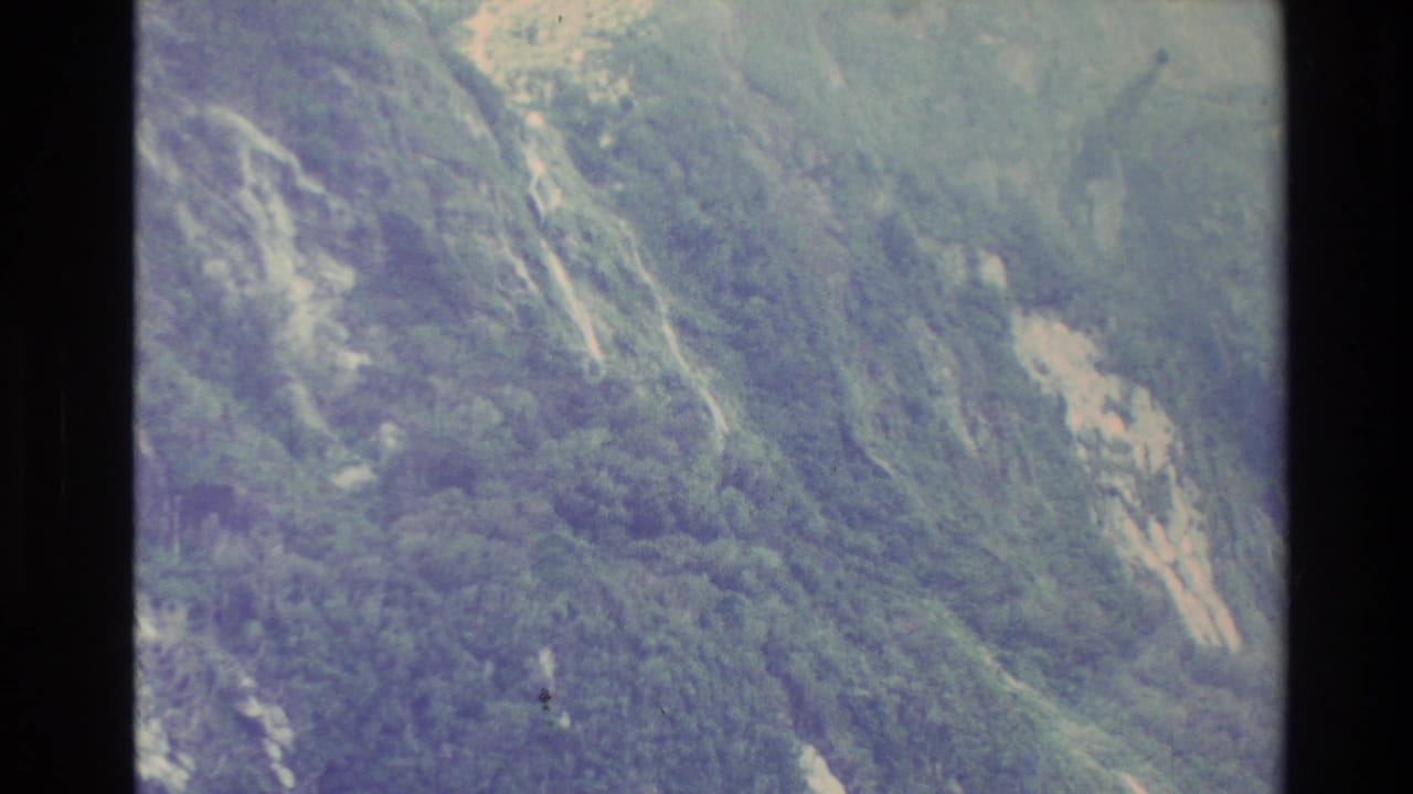 New Zealand 1982 8mm frame showing a green mountainside with exposed rock patches and soft faded color.
