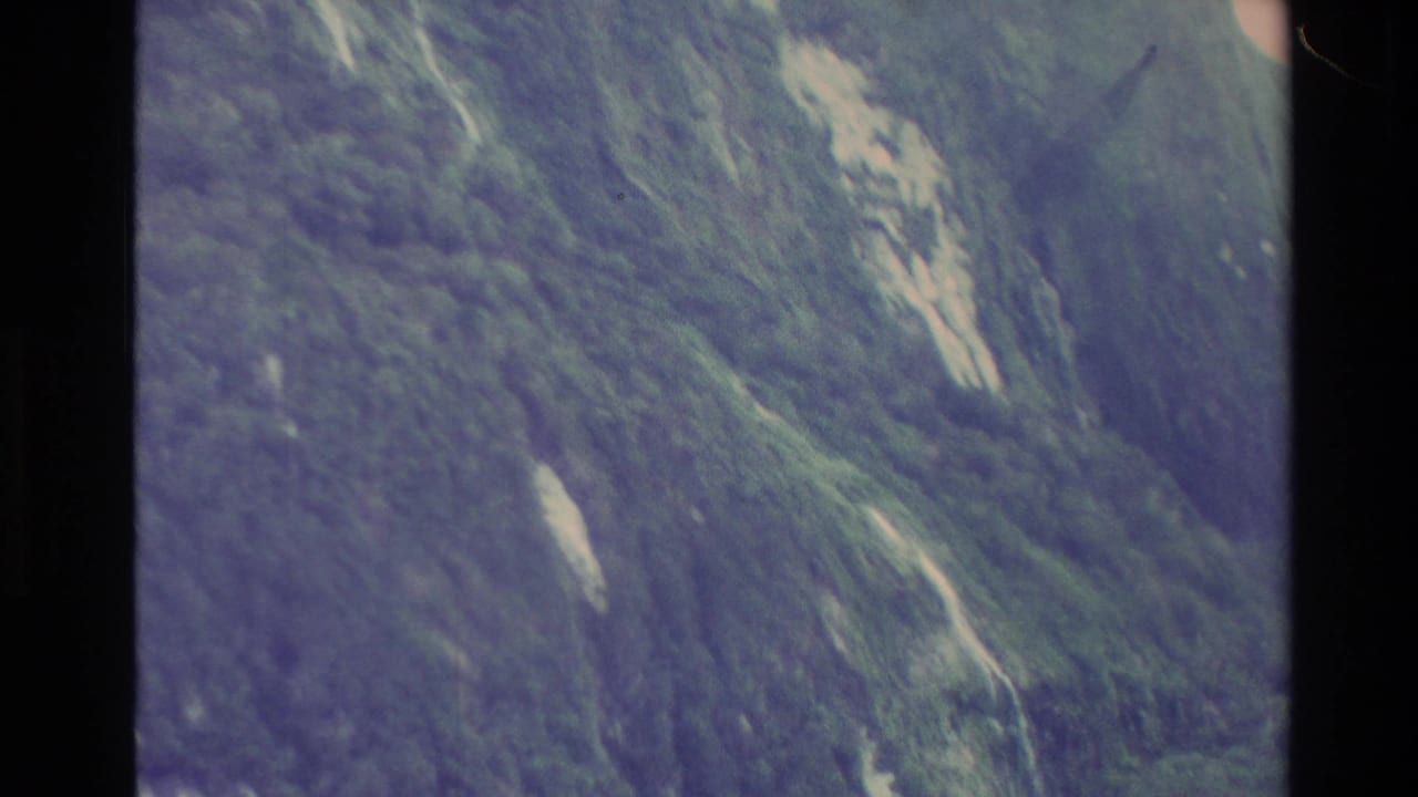 Steep green mountain face with light rock streaks and visible film border.