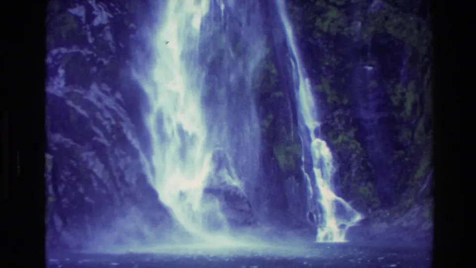 1982 New Zealand 8mm frame showing the waterfall widening as it reaches the pool or inlet at the cliff base.