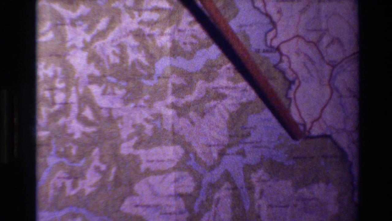 Wooden pointer rests over a topographical map with blue waterways and dark projection borders.
