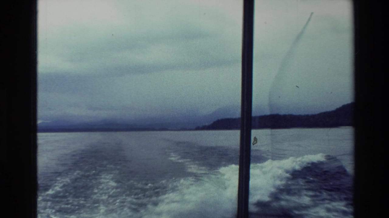 1982 New Zealand 8mm travel footage showing a boat wake through window framing, with open water, low shore, and overcast sky.