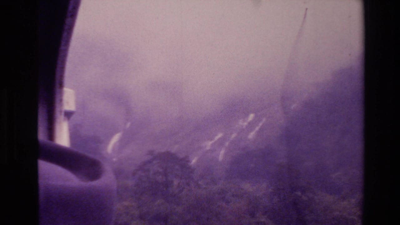 Smoke and haze over mountains viewed beside a dark window frame.