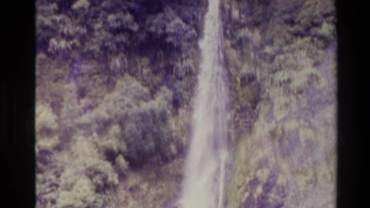 Closer view of the upper and middle waterfall against trees and rock.