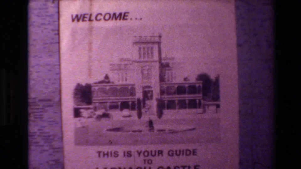 Close-up frame of the Larnach Castle guide pamphlet, with the castle drawing centered and text partly visible.