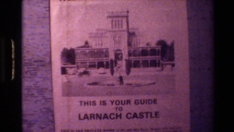 Final frame of the New Zealand travel clip showing the Larnach Castle guide title and printed castle artwork on the pamphlet.
