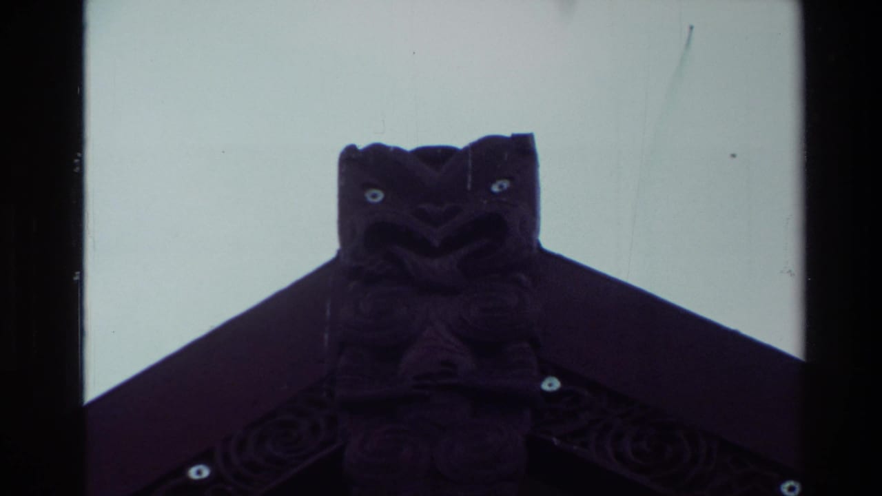 Close view of a dark carved roof figure against a pale sky.