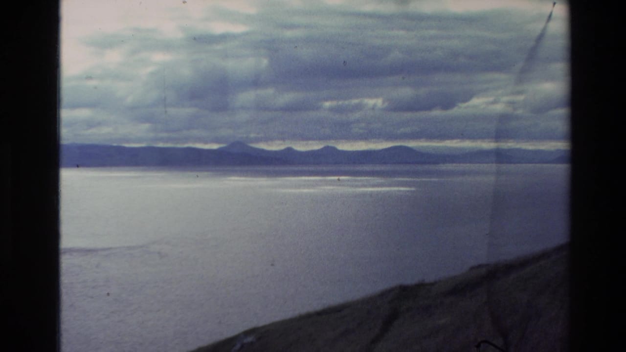 Open water and distant mountains with a dark sloped foreground edge.