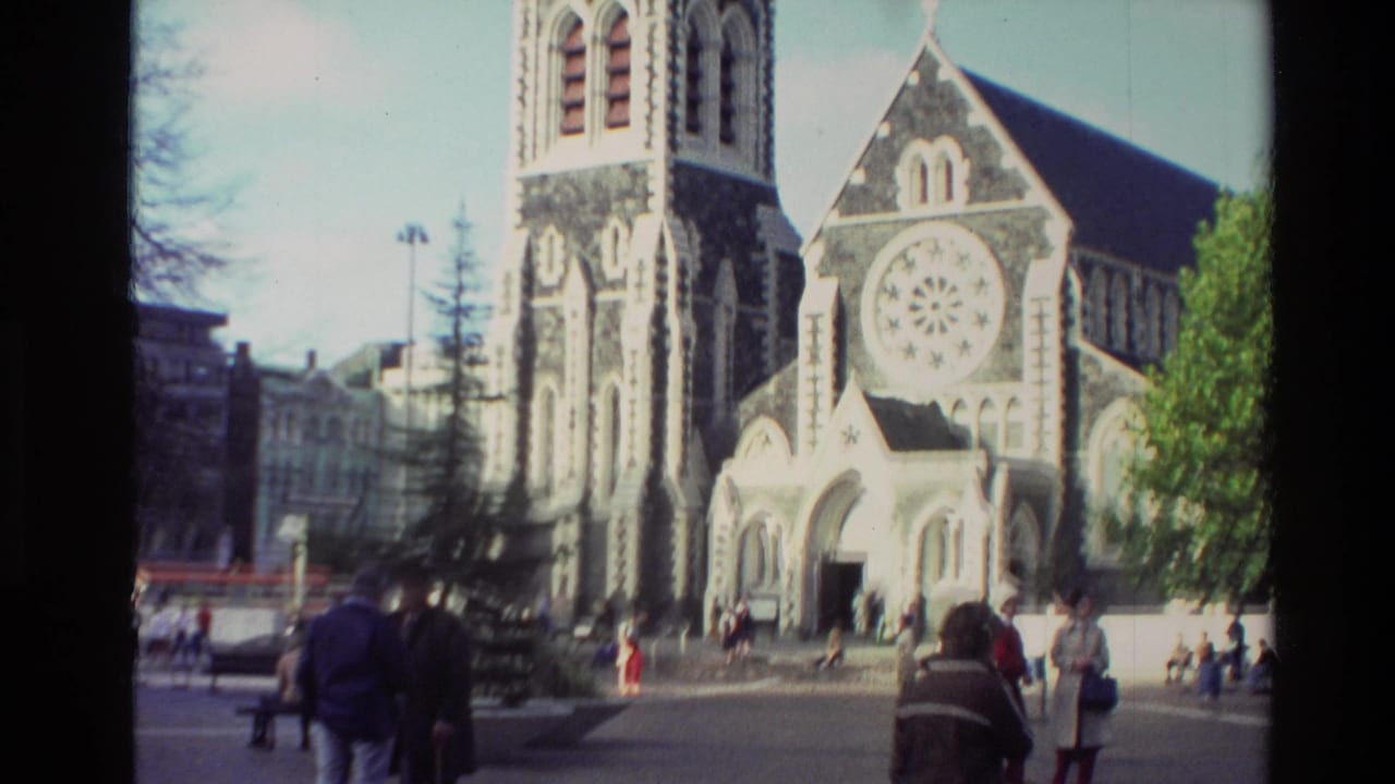 A stone church with a tower and rose window stands behind people in a plaza.