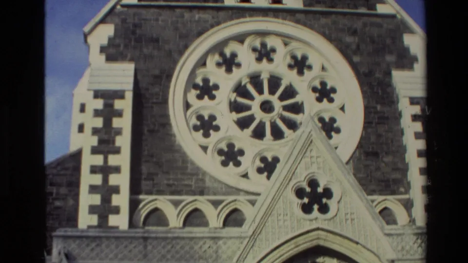 1982 New Zealand 8mm frame showing a close view of a church rose window with floral tracery and stone facade details.