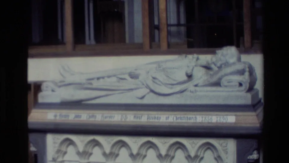 1982 New Zealand 8mm frame showing a close view of a carved reclining bishop effigy and inscription panel inside a church.