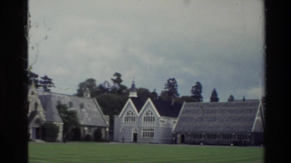 1982 8mm view of Christ's College campus buildings across a large green lawn in New Zealand.