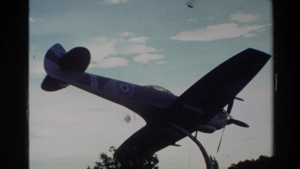 1982 New Zealand frame showing the mounted aircraft from below, with propeller, wings, roundel marking, pedestal, treetops, and sky.