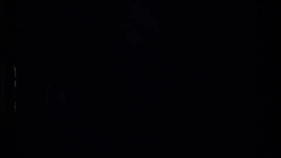 Underexposed 8mm transition frame from the New Zealand clip, with little visible detail beyond dark film area and edge marks.