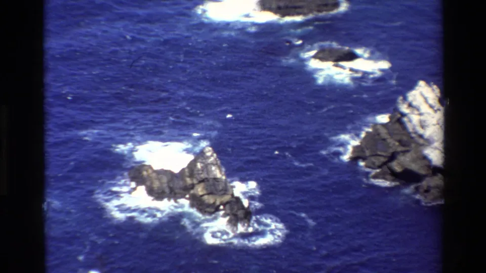 Big Sur, California, ocean detail from 1980 8mm footage, with sea stacks, breaking surf, and rugged rock forms.
